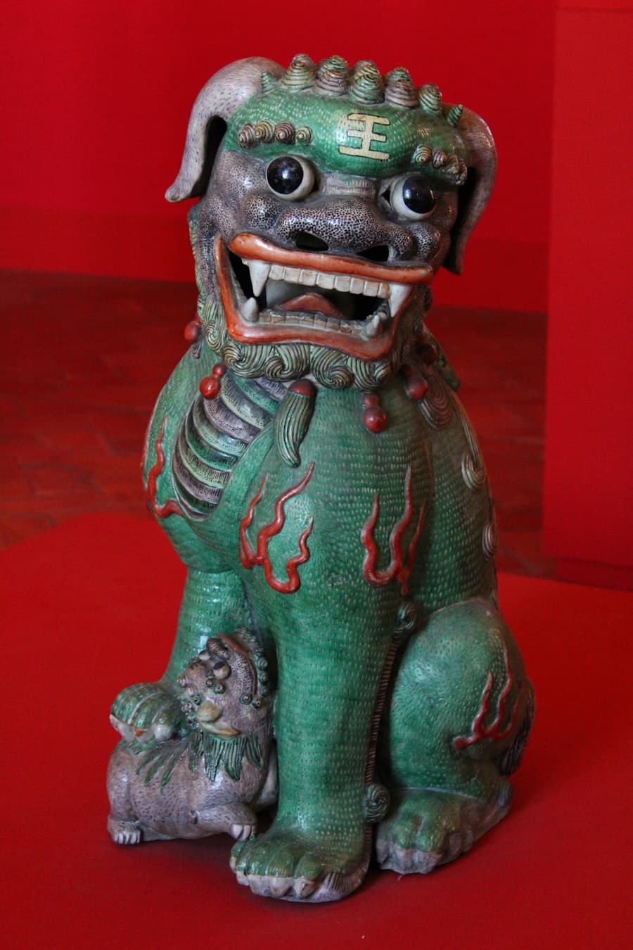 Tượng nghê gốm men xanh trên nền đỏ